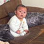 Mabel joined the competition — help win amazing prizes! baby, child, infant, couch, sofa, pillow, white_clothing, onesie, indoor, home, furniture, sitting, young_child, curious, expression, brown, gray, soft_texture, casual, portrait