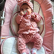 Lorena is registered to the contest to win money with this photo: baby, infant, pacifier, pink_clothing, headband, baby_seat, carpet, indoors, cute, child, plush, soft_texture, relaxing, portrait, small_person, sock, cozy, baby_girl, comfort, wearing