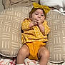 baby, child, infant, yellow_clothing, headband, pillow, blanket, bed, footwear, leopard_print, socks, indoors, resting, cute, patterned, comfort, soft_furnishing, sleepwear, person, portrait