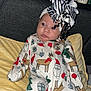 baby, infant, pajamas, christmas_theme, headband, bow, blanket, bottle, medicine, sitting, indoors, curious_expression, furniture, shelf, holiday, cute, child, person, portrait, clothing