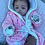 baby, child, pink_robe, heart_pattern, bow, blanket, mitten, indoor, cute, portrait, infant, soft_texture, cozy, face, person, headwear, sitting, hand, leg, expression