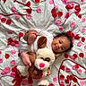 Bailee joined the competition — help win amazing prizes! baby, infant, smile, stuffed_animal, dog_toy, rose_petals, heart_beads, white_sheet, cute, happy, child, playful, soft_toy, pink, red, lying_down, portrait, indoors, adorable, young_child