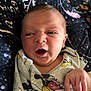 baby, newborn, infant, face, expression, mickey_mouse, cartoon, shirt, clothing, hand, lying_down, blanket, pattern, cute, child, portrait, skin, indoors, person, closeup