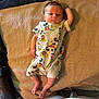 baby, infant, mickey_mouse, onesie, blanket, fabric, person, lying_down, clothing, cute, newborn, child, indoor, texture, pattern, foot, hand, face, head, soft