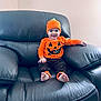 Brayan joined the competition — help win amazing prizes! toddler, child, pumpkin_costume, orange_clothing, hat, smile, barefoot, black_leather_chair, indoor, cute, happy, holiday, festive, seasonal, portrait, sitting, baby, cozy, home, fun