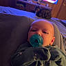 Samuel joined the competition — help win amazing prizes! baby, pacifier, onesie, infant, cat, bed, television, indoor, wood_paneling, furniture, animal, pet, living_room, blanket, sleepwear, child, cute, home, relaxing, soft_lighting