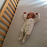 baby, crib, wooden_crib, onesie, infant, sleepwear, sleeping_baby, bedroom, mattress, child, newborn, cute, stretching, peaceful, indoor, soft_light, pajamas, dinosaur_print, resting, baby_clothes