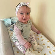 Livia participe au concours pour gagner de l'argent avec cette photo : baby, child, smiling, headband, floral, leggings, sitting, changing_table, indoor, cute, happy, person, infant, wall, soft_light, apparel, footwear, pattern, cozy, playful