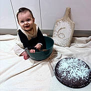 Emy a rejoint le concours — aidez-le/la à gagner de superbes lots ! baby, baking, blanket, bowl, cabinet, cake, child, cooking, cute, floor, flour, happy, indoor, kitchen, person, powdered_sugar, sitting, smiling, whisk, wooden_board