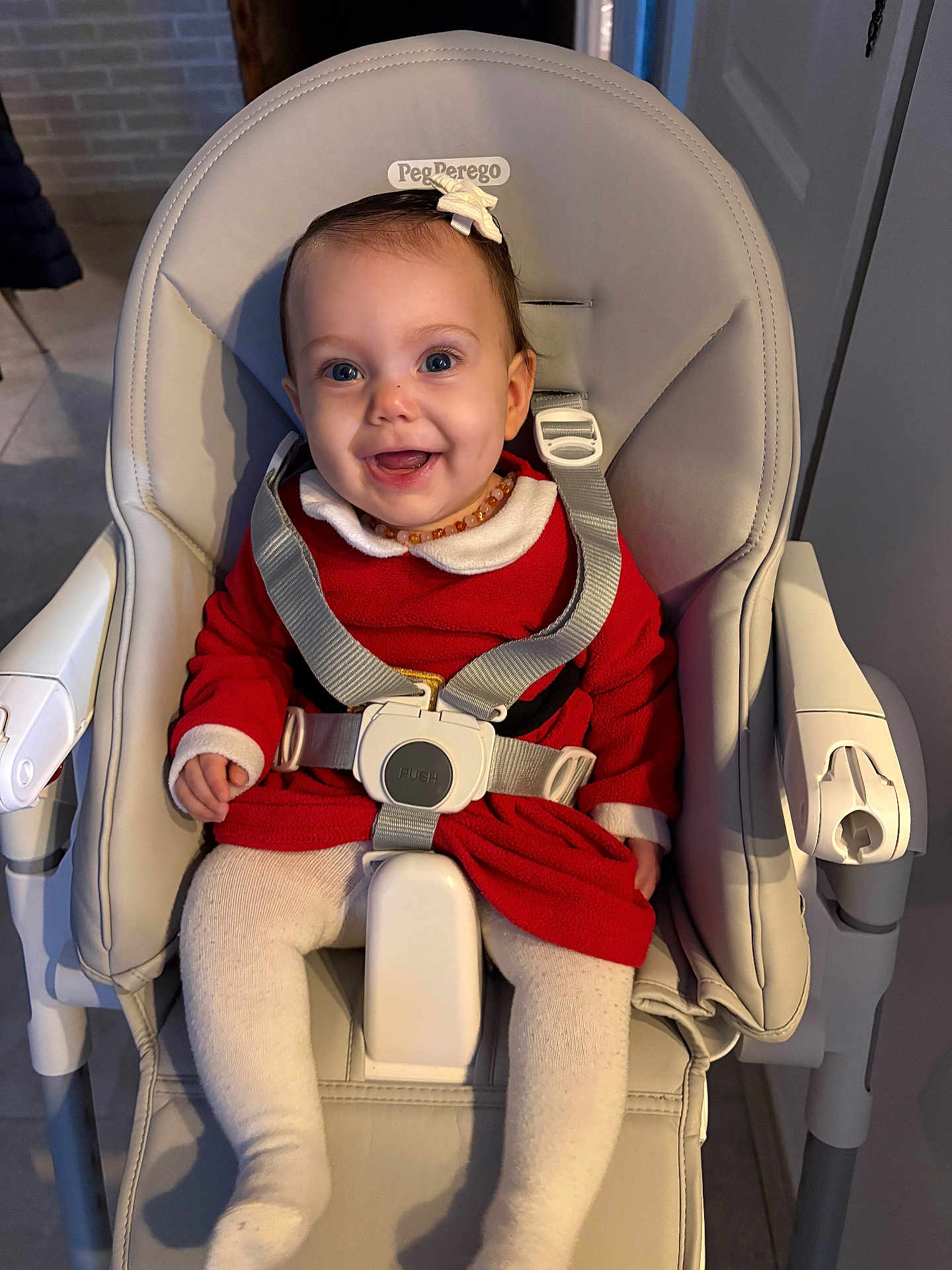 Emy participe au concours pour gagner de l'argent avec cette photo : baby, child, high_chair, smile, red_dress, white_tights, seatbelt, indoor, happy, face, person, young_child, cute, baby_girl, clothing, furniture, sitting, headwear, expression, infant