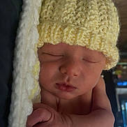 Jamie is registered to the contest to win money with this photo: baby, newborn, sleeping, hat, knitted_hat, blanket, yellow, soft, cozy, infant, peaceful, cute, sleep, child, portrait, hand, skin, indoors, wooden_background, closeup