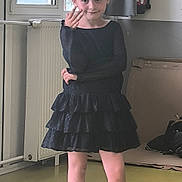 Alicia participe au concours pour gagner de l'argent avec cette photo : child, girl, black_dress, crown_headband, standing, indoors, window, radiator, cardboard_box, floor, sandals, pose, smile, curtain, playful, young, person, casual, confident, light