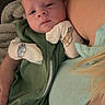 Hayes is registered to the contest to win money with this photo: baby, infant, child, person, green_outfit, mittens, car_print, blanket, couch, tattoo, adult, closeup, resting, indoor, comfort, snug, portrait, sleepy, skin, hair