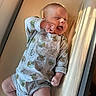 apparel, baby, baby_yoda, changing_pad, child, cute, expression, footwear, hand, happy, indoors, infant, light, lying_down, onesie, playful, skin, smiling, socks, sunlight