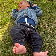 Jackson joined the competition — help win amazing prizes! baby, infant, grass, outdoor, knitted_sweater, blue_clothing, pants, barefoot, relaxed, sunlight, nature, child, person, casual_wear, greenery, daylight, lying_down, cute, small_child, peaceful