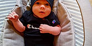 River is registered to the contest to win money with this photo: baby, infant, child, champion_brand, black_clothing, hat, onesie, baby_seat, padded_seat, footwear, socks, wooden_floor, indoor, cute, portrait, young_child, apparel, headwear, expression, relaxed