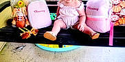 Chesney joined the competition — help win amazing prizes! toddler, child, porch_swing, black_swing, pink_bags, embroidered_name, scarecrow_doll, decorative_pillows, green_grass, outdoor, concrete_floor, purple_bow, white_outfit, smiling, sitting, summer, sunlight, cute, happy, playful