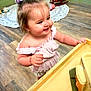 Chesney is registered to the contest to win money with this photo: toddler, child, bow, pink_clothing, table, wooden_floor, rocking_chair, indoor, smiling, curious, hair, face, hand, furniture, playroom, young_child, cute, person, floor, room