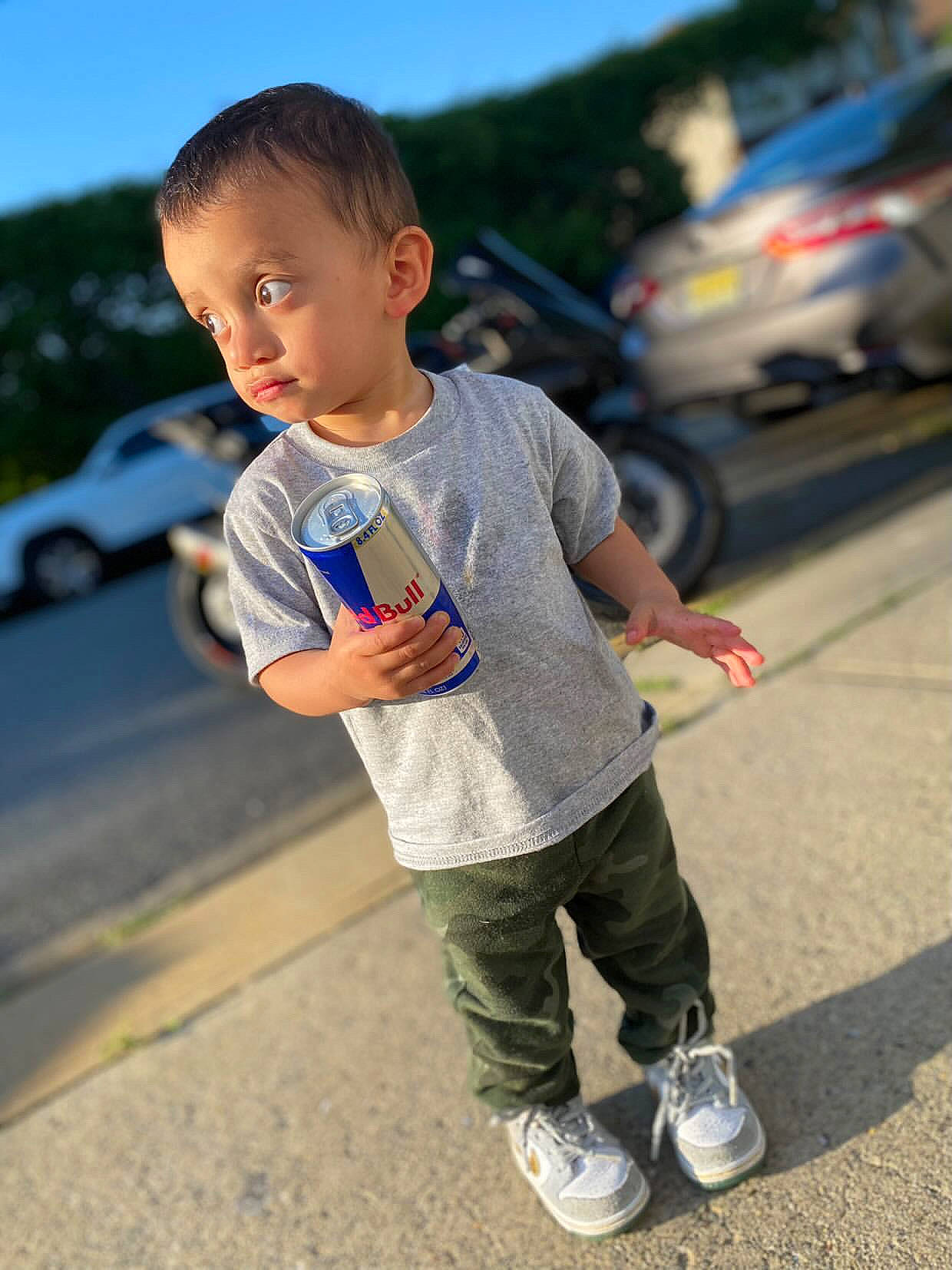 Jacob is registered to the contest to win money with this photo: asphalt, car, child, cool, footwear, fun, gesture, hairstyle, hand, happy, leg, leisure, person, sky, sneakers, standing, summer, t_shirt, tire, toddler