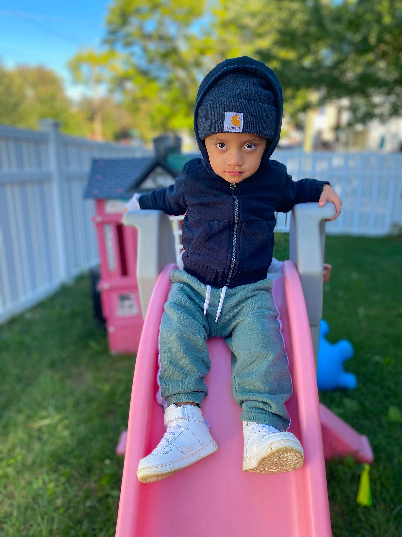 Jacob is registered to the contest to win money with this photo: baby_toddler_clothing, cap, child, chute, electric_blue, fence, fun, grass, headwear, jacket, leisure, magenta, outerwear, person, personal_protective_equipment, pink, purple, recreation, shorts, sitting