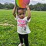 toddler, child, ball, rainbow, grass, park, outdoor, cloudy_sky, trees, greenery, white_shoes, black_leggings, cute_clothing, minnie_mouse, daisy_duck, playing, holding, standing, young_child, nature