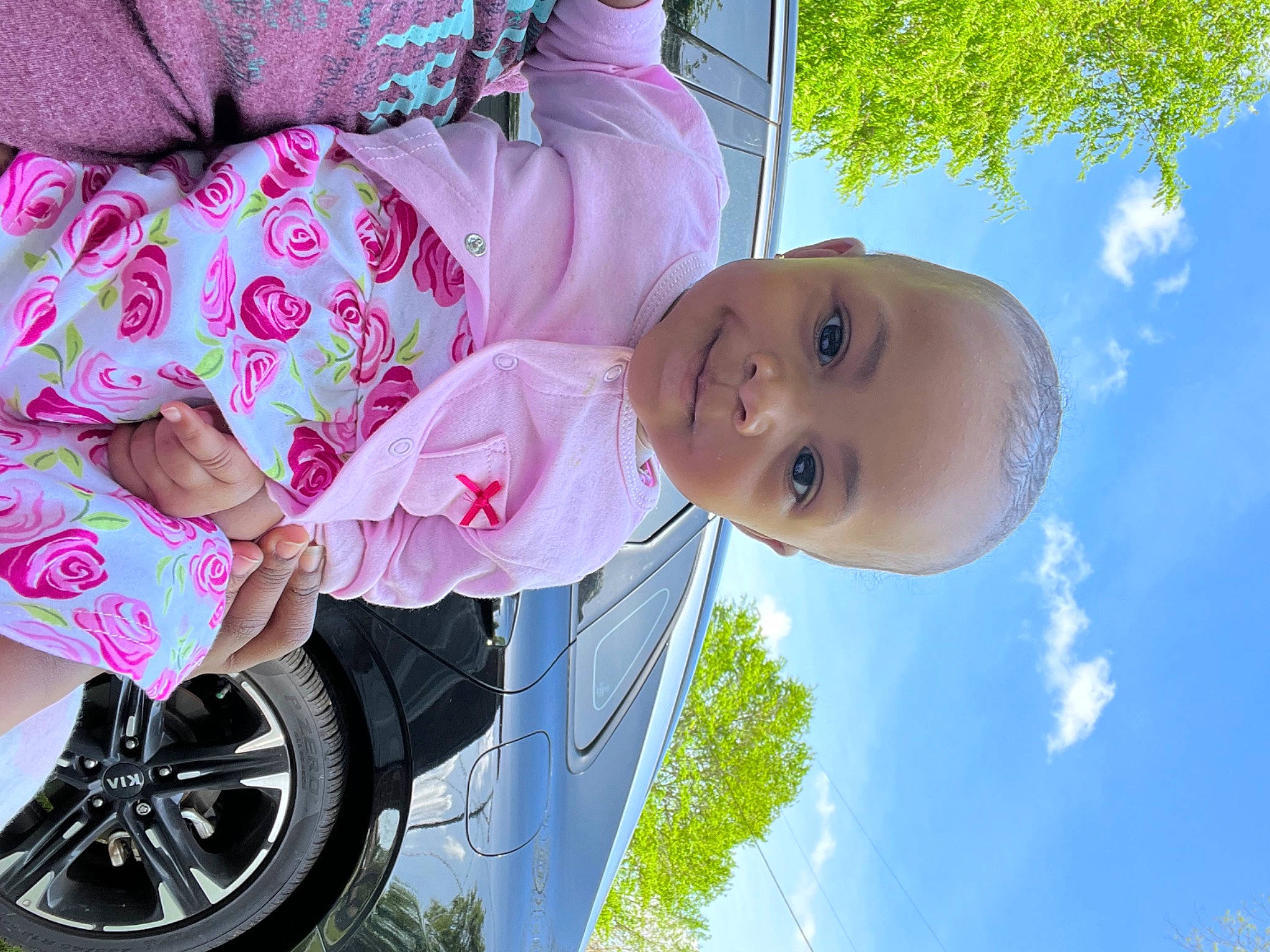 Adilynn is registered to the contest to win money with this photo: arm, automotive_tire, cloud, dress, facial_expression, green, hand, happy, head, human_body, mammal, person, pink, plant, product, sky, smile, tire, tree, wheel