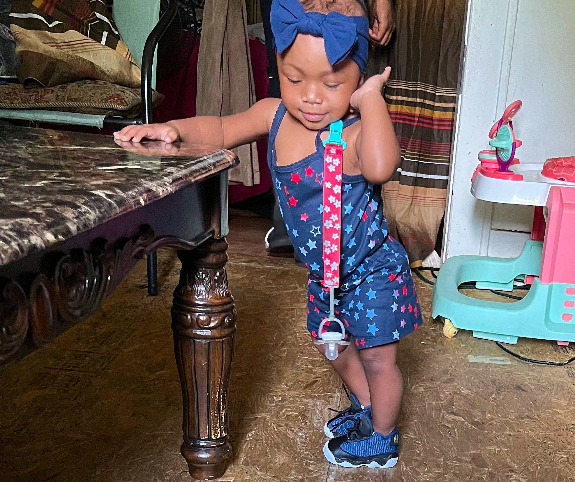 Adilynn is registered to the contest to win money with this photo: baby_toddler_clothing, bench, blue, child, electric_blue, eyewear, fashion_accessory, flooring, folk_instrument, fun, headwear, human_leg, leisure, pattern, person, room, sitting, standing, t_shirt, table