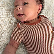 Hakeem joined the competition — help win amazing prizes! baby, infant, smiling, curly_hair, striped_clothing, onesie, lying_down, fluffy_rug, soft_texture, cute, happy, child, skin, face, arm, portrait, indoors, closeup, young, person