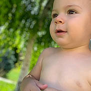 Christian a rejoint le concours — aidez-le/la à gagner de superbes lots ! baby, blurred_background, child, closeup, cute, daylight, expression, face, greenery, hands, innocence, nature, outdoor, person, portrait, skin, summer, sunlight, tree, young