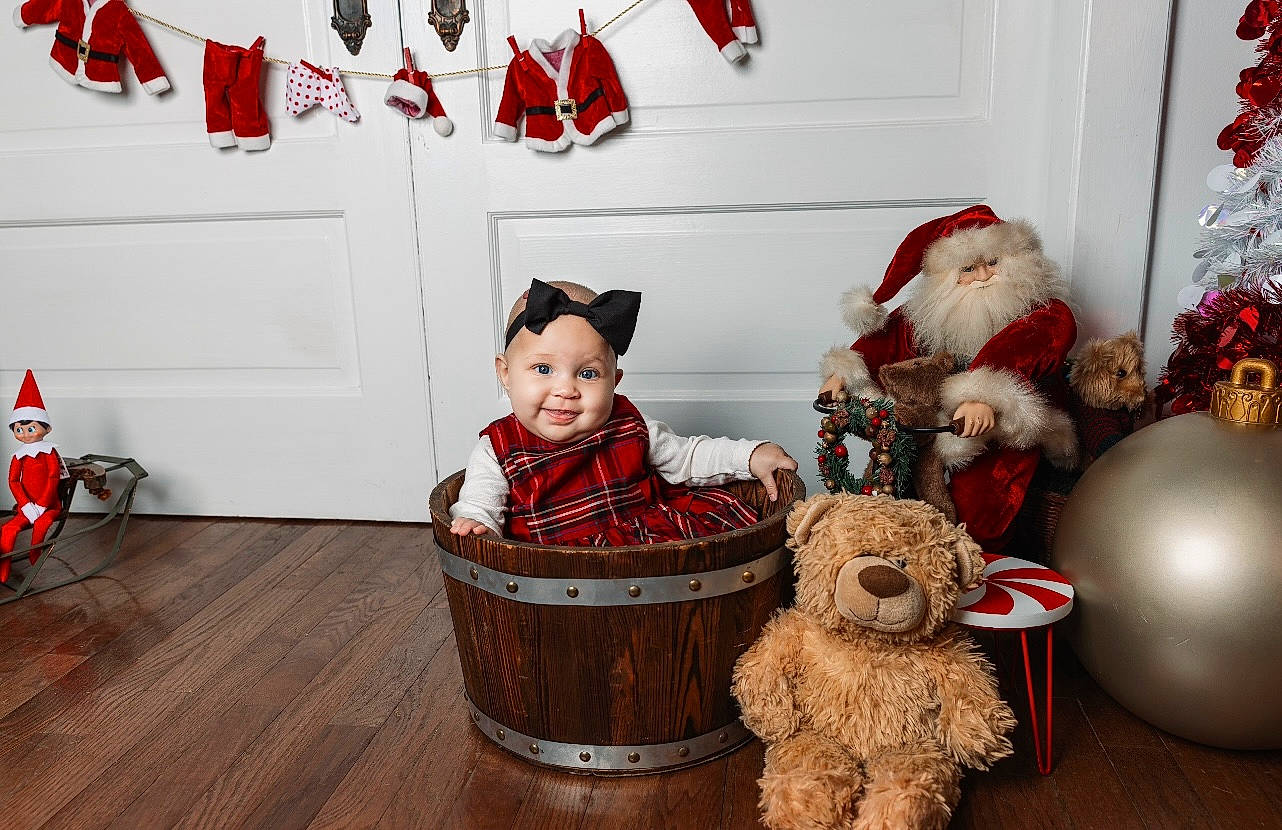 Zayla is registered to the contest to win money with this photo: basket, carmine, christmas, costume_hat, event, fur, happy, hat, headwear, holiday, joy, ornament, person, red, room, smile, stuffed_toy, teddy_bear, toddler, toy
