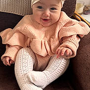 Eleanor is registered to the contest to win money with this photo: baby, infant, child, smiling, sitting, sweater, knitted_tights, white_turban, bow, armchair, brown_furniture, cozy, indoors, cute, happy, portrait, soft_lighting, hand, face, person