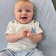 Alfie is registered to the contest to win money with this photo: baby, child, smiling, happy, face, clothing, blue_blanket, striped_pants, white_shirt, sitting, hands, cute, infant, portrait, indoor, soft_texture, light_blue, button_detail, young, person
