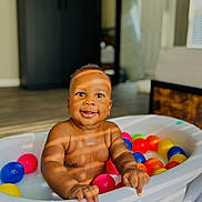 Amiel is registered to the contest to win money with this photo: baby, tub, colorful_balls, indoor, smiling, sunlight, shadow, child, play, happy, skin, face, hand, floor, furniture, window, room, toy, infant, portrait