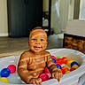baby, tub, colorful_balls, indoor, smiling, sunlight, shadow, child, play, happy, skin, face, hand, floor, furniture, window, room, toy, infant, portrait