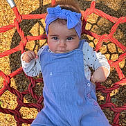 Lexie a rejoint le concours — aidez-le/la à gagner de superbes lots ! baby, child, toddler, overalls, headband, bow, rope_swing, playground, outdoor, sunlight, wood_chips, clothing, person, face, expression, hands, feet, casual, leisure, summer