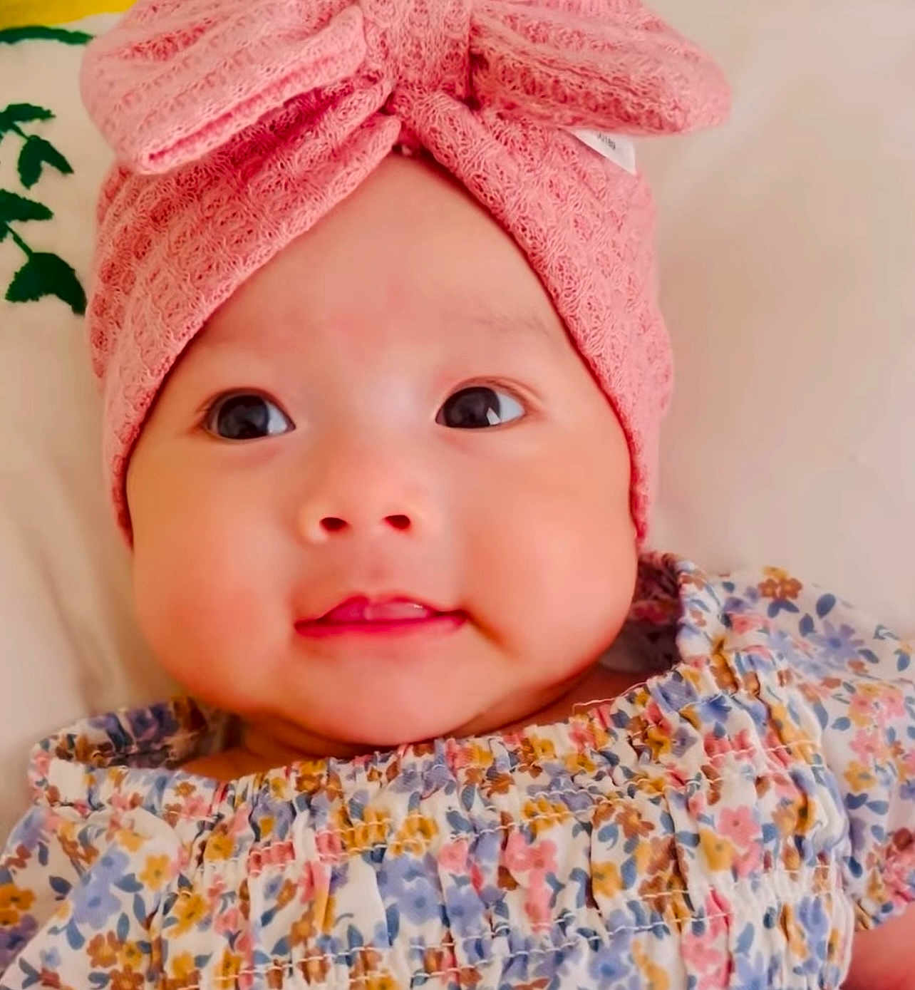 Hannah joined the competition — help win amazing prizes! baby, infant, child, face, pink_hat, knitted_hat, bow, floral_outfit, cute, smile, chubby_cheeks, portrait, closeup, indoors, soft_lighting, happy, young_child, fashion, headwear, eyes