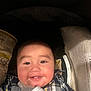 Jose is registered to the contest to win money with this photo: baby, smiling, plaid_shirt, bottle, car_seat, infant, face, child, happy, cute, indoors, person, young, food, feeding, closeup, cheerful, childcare, seatbelt, clothing