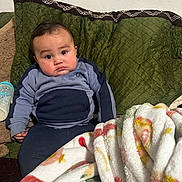 Jose joined the competition — help win amazing prizes! baby, child, couch, blanket, bottle, green_cushion, clothing, sitting, indoor, face, expression, person, portrait, toddler, sweater, soft_blanket, cozy, resting, cute, home