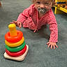 Koura is registered to the contest to win money with this photo: baby, child, pacifier, toy, stacking_rings, pink_clothing, crawling, carpet, indoor, yellow_shelf, wooden_toys, floor, curious, polka_dot, infant, playtime, person, young_child, home, bright_colors