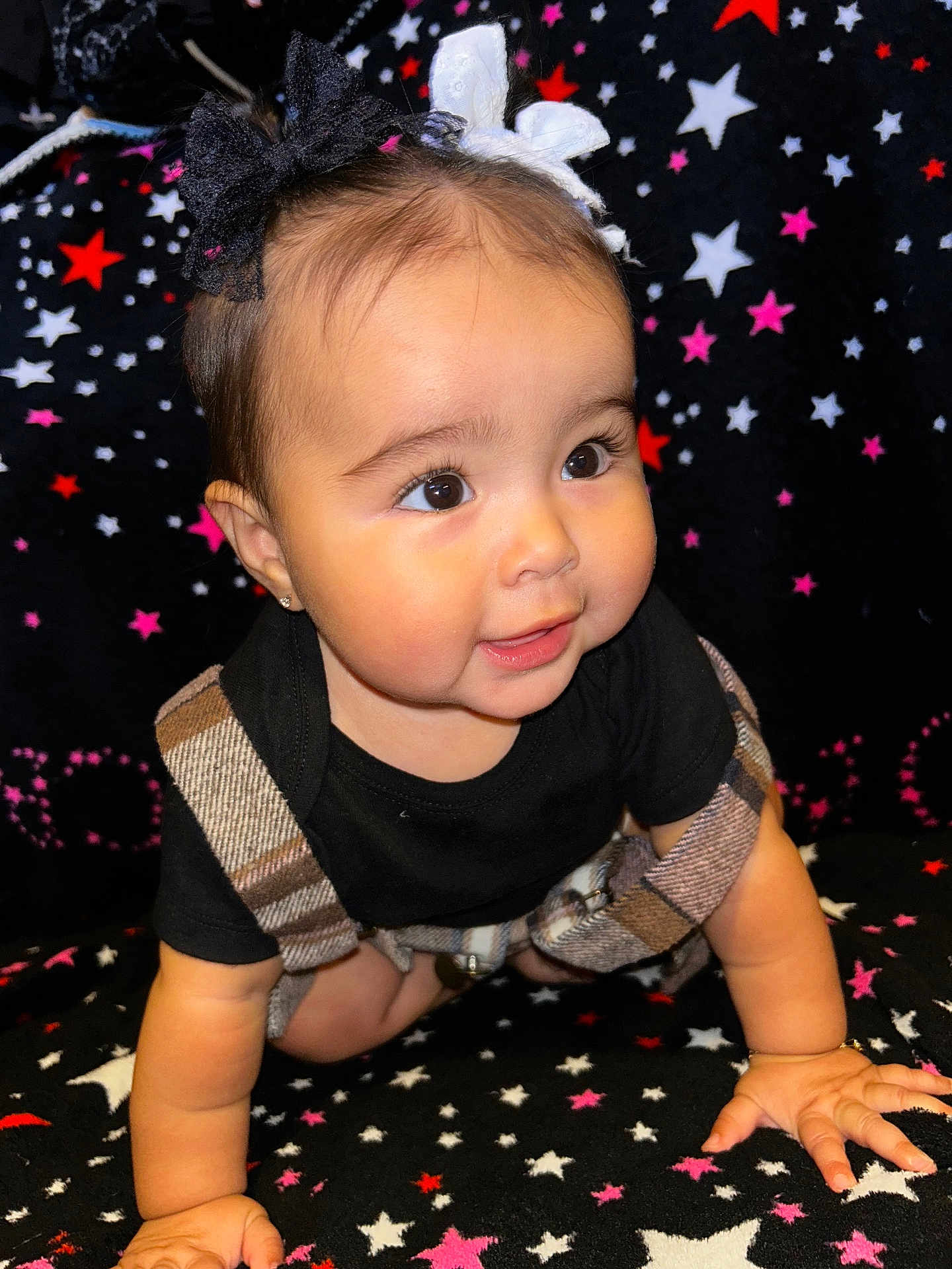 Valenciannah joined the competition — help win amazing prizes! baby, child, crawling, black_shirt, plaid_overalls, bows, face, eyes, hands, star_pattern, blanket, cute, infant, indoors, portrait, smiling, cheeks, person, clothing, happy
