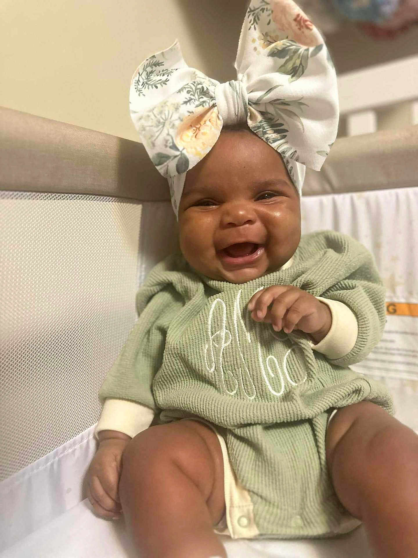 Anna-Lisa is registered to the contest to win money with this photo: baby, baby_clothes, bow, child, cozy, crib, cute, fabric, face, green_clothing, hand, happy, headwear, indoors, infant, legs, portrait, sitting, skin, smiling