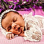 baby, closeup, cozy, cute, delicate, face, hands, headband, indoors, infant, lace, newborn, peaceful, pink_blanket, portrait, purple_flowers, resting, serene, sleeping, soft_texture