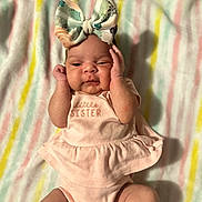 Anna-Lisa is registered to the contest to win money with this photo: adorable, baby, baby_clothes, blanket, bow, child, cute, expression, hands_near_face, headband, indoors, infant, little_sister, lying_down, newborn, pink_outfit, portrait, sleepwear, soft_lighting, striped_blanket