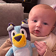 Jaxx joined the competition — help win amazing prizes! baby, plush_toy, couch, hand, face, infant, furniture, indoors, child, person, cute, soft_toy, holding, seated, expression, cozy, clothing, blanket, home, portrait