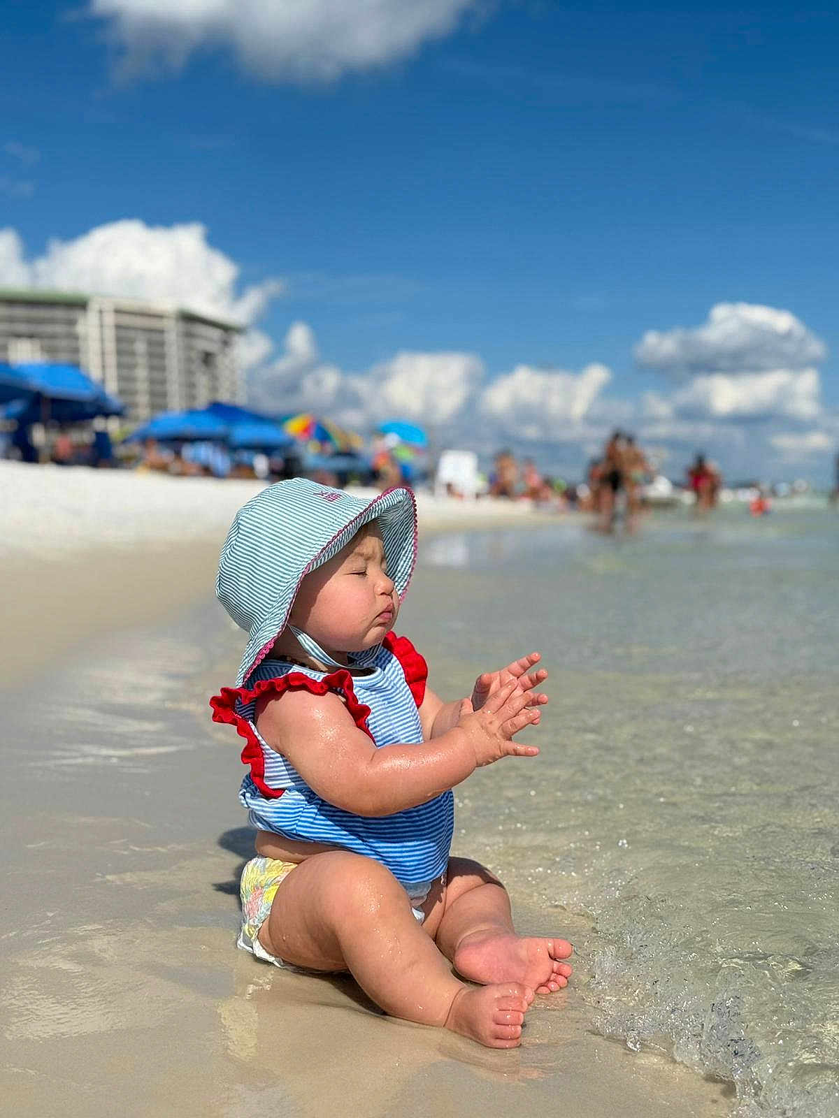 Adelyn joined the competition — help win amazing prizes! baby, child, beach, water, sand, sunhat, swimsuit, ocean, waves, summer, vacation, outdoor, sunny, sky, clouds, people, shore, relaxing, cute, toddler