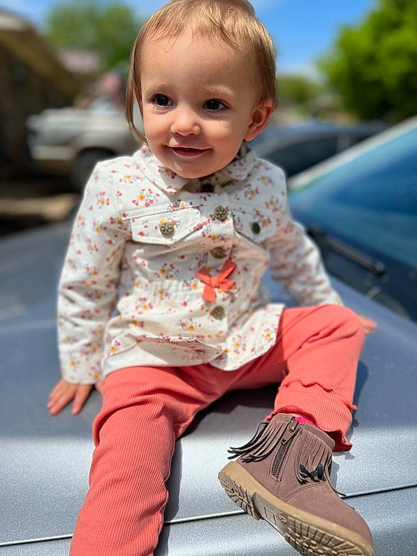 Olive is registered to the contest to win money with this photo: baby, baby_toddler_clothing, car, face, happy, head, joint, joy, leg, leisure, orange, outerwear, people, person, shoulder, skin, sleeve, smile, standing, summer