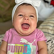 Kemiah joined the competition — help win amazing prizes! baby, child, smiling, happy, headband, bow, pink_shirt, puma_logo, indoor, cushion, pattern, cheeks, tongue, person, portrait, cute, infant, clothing, seated, closeup