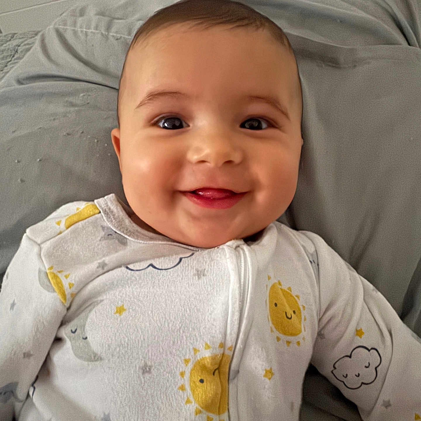 Bryan joined the competition — help win amazing prizes! baby, smiling, face, infant, onesie, sleepwear, bed, pillow, cute, child, happy, portrait, indoors, person, sleepy_cloud, sun, stars, clothing, lying_down, closeup