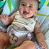 baby, smiling, infant, child, seat, baby_chair, tank_top, happy, face, skin, cute, sitting, safety_harness, pattern, animal_print, puma_logo, furniture, indoors, bright, colorful