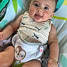 Bryan is registered to the contest to win money with this photo: animal_print, arms, baby, baby_seat, child, clothing, colorful, cute, fabric, face, happy, harness, indoor, infant, legs, pattern, playful, seat, sleeveless_top, smiling